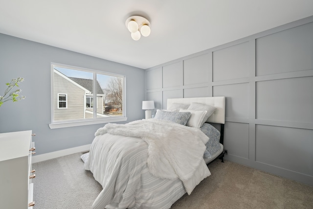 bedroom with light carpet, baseboards, and a decorative wall