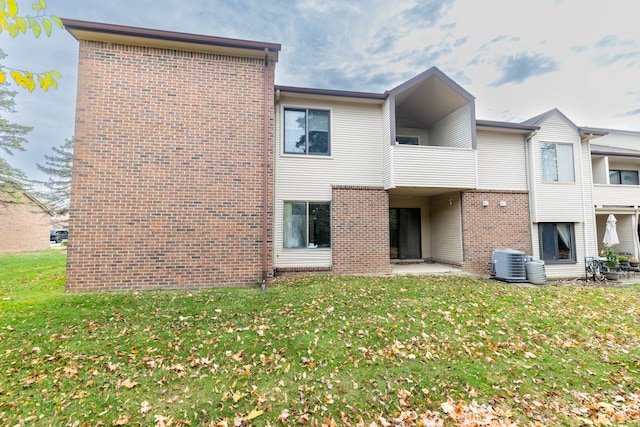 rear view of house featuring a yard, a balcony, a patio, and central AC unit