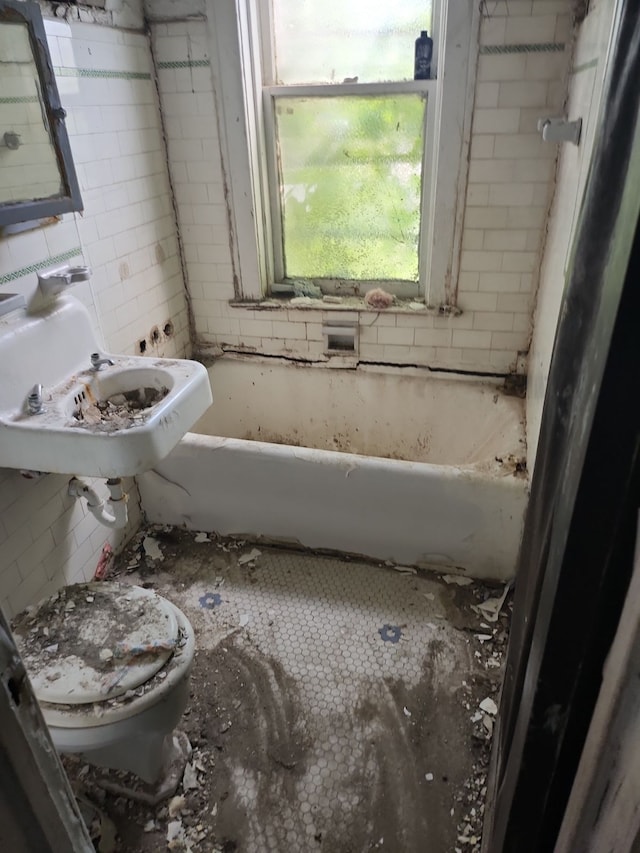 bathroom with sink, toilet, and a tub to relax in