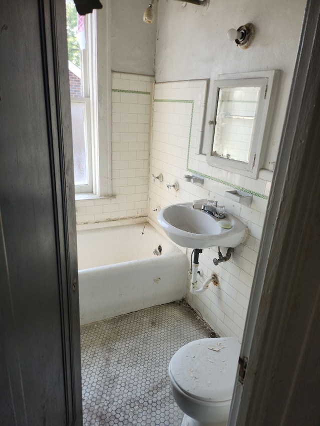 bathroom with a tub, a wealth of natural light, and tile walls