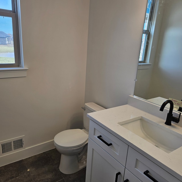 bathroom featuring vanity, a wealth of natural light, and toilet