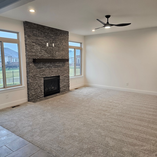 unfurnished living room featuring ceiling fan, a fireplace, and light carpet