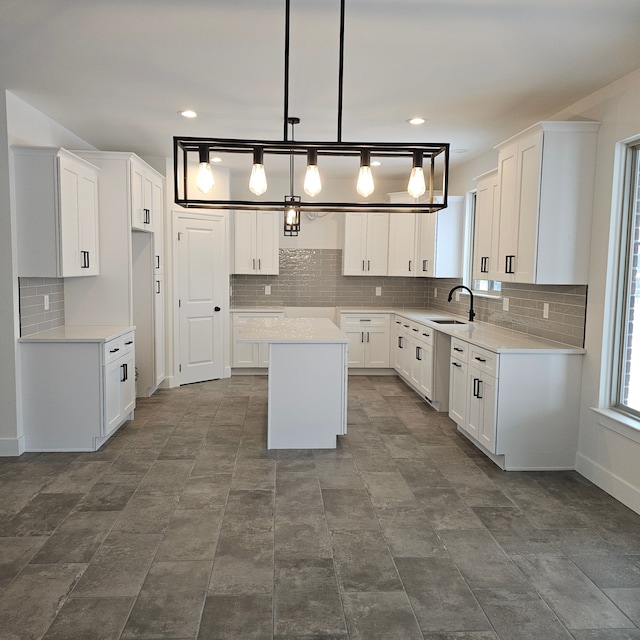 kitchen featuring sink, white cabinetry, a kitchen island, pendant lighting, and backsplash