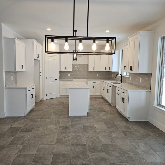 18240 Stallmann Dr, Macomb, MI 48042 - kitchen featuring a kitchen island, decorative backsplash, a sink, white cabinets, and decorative light fixtures