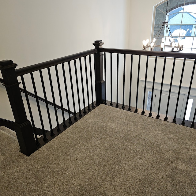 stairway featuring an inviting chandelier and carpet floors