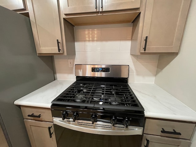 kitchen with light stone countertops, gas range, and tasteful backsplash