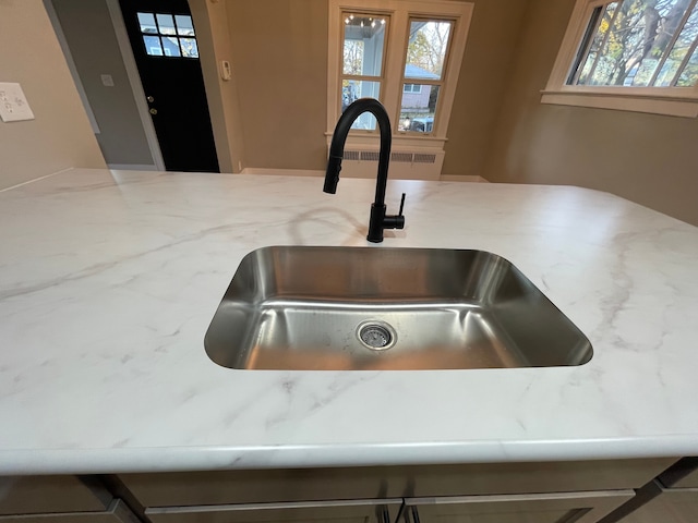 interior details featuring light stone countertops and sink