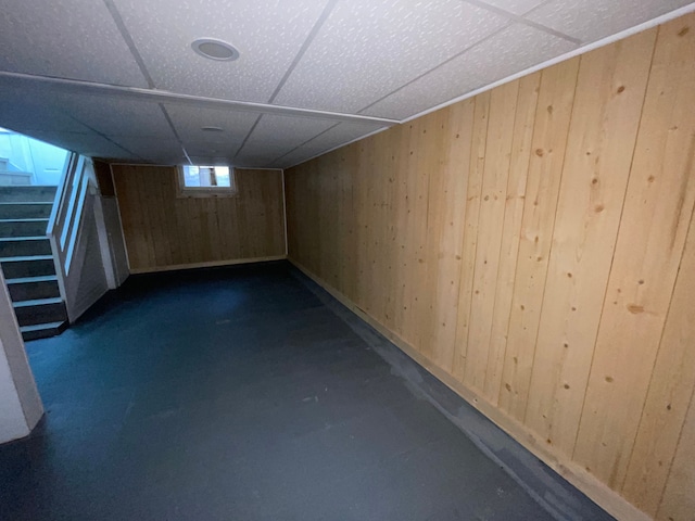 basement with a paneled ceiling and wooden walls