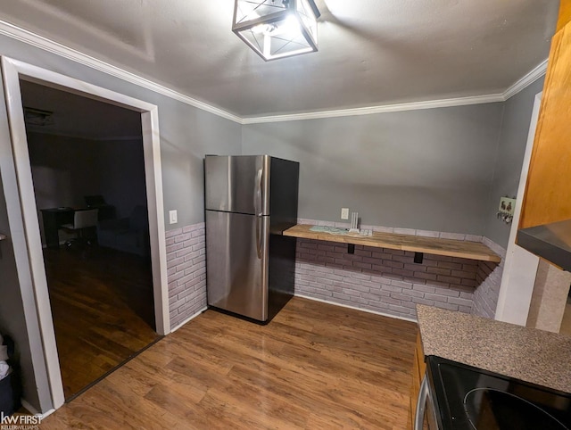 kitchen with hardwood / wood-style flooring, crown molding, and appliances with stainless steel finishes