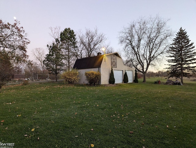 property exterior at dusk featuring a lawn, an outdoor structure, and a garage