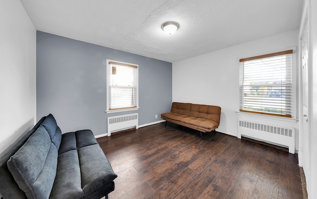 sitting room featuring radiator, a wealth of natural light, and dark wood-type flooring