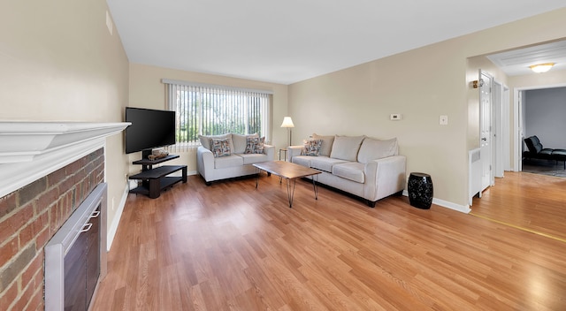 living room with a brick fireplace and light hardwood / wood-style flooring