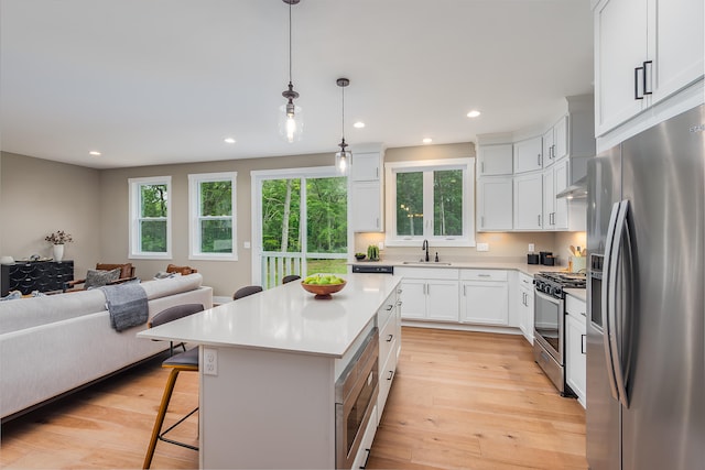 kitchen with pendant lighting, a breakfast bar, a kitchen island, white cabinetry, and stainless steel appliances