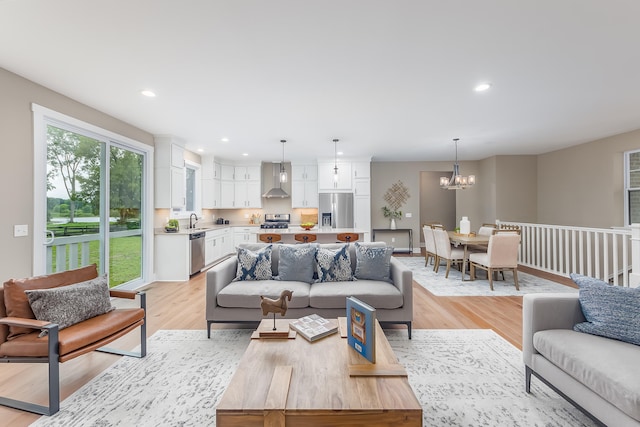 living room with light wood-type flooring, sink, and an inviting chandelier