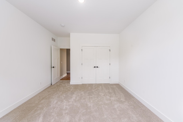 unfurnished bedroom with light colored carpet and a closet