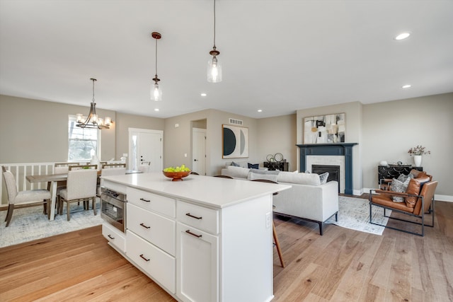 kitchen featuring white cabinetry, an inviting chandelier, light hardwood / wood-style flooring, decorative light fixtures, and a kitchen island