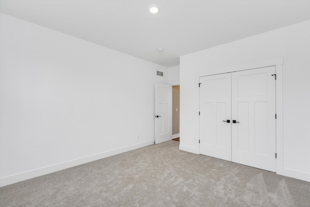 unfurnished bedroom with light carpet and a closet