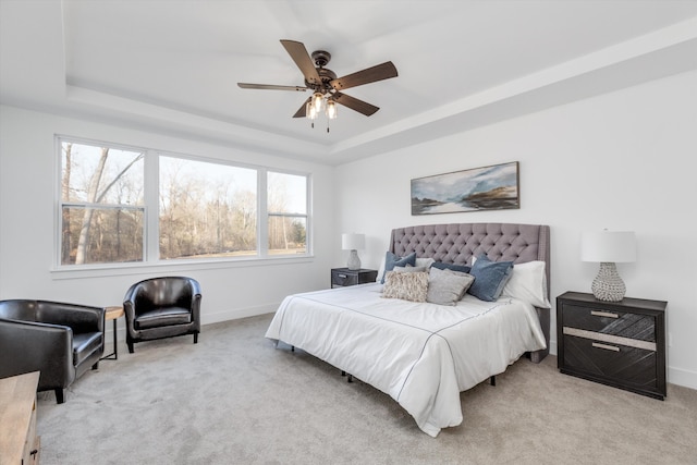 bedroom featuring light colored carpet, a raised ceiling, and ceiling fan