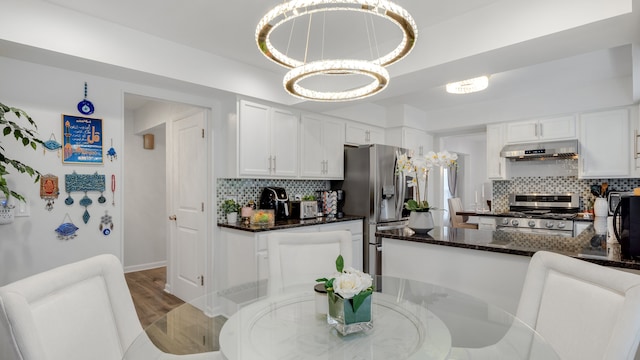 kitchen featuring tasteful backsplash, white cabinetry, stainless steel appliances, and decorative light fixtures