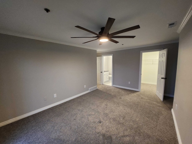 unfurnished bedroom with a walk in closet, crown molding, ceiling fan, carpet floors, and a closet