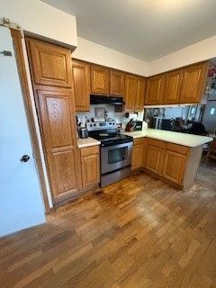 kitchen with kitchen peninsula, dark hardwood / wood-style flooring, and stainless steel range with electric stovetop