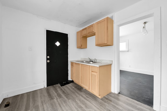 kitchen with light brown cabinets, sink, and light hardwood / wood-style flooring