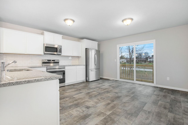 kitchen with wood-type flooring, appliances with stainless steel finishes, white cabinetry, and sink