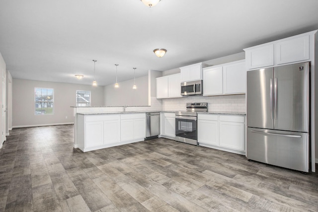 kitchen featuring pendant lighting, light wood-type flooring, white cabinetry, and appliances with stainless steel finishes