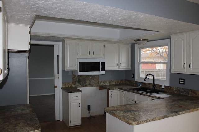 kitchen featuring white cabinets, dark hardwood / wood-style flooring, sink, and a textured ceiling