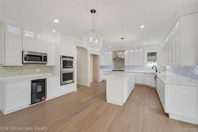 5245 Buell Dr, Commerce Twp, MI 48382 - kitchen with wine cooler, stainless steel appliances, a chandelier, backsplash, and wall chimney range hood