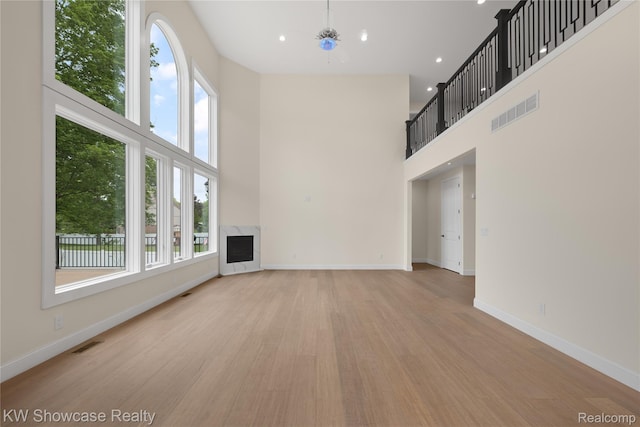 5245 Buell Dr, Commerce Twp, MI 48382 - unfurnished living room featuring a high ceiling, light wood-style floors, a fireplace, baseboards, and heating unit