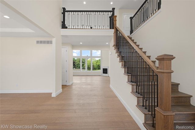 5245 Buell Dr, Commerce Twp, MI 48382 - stairs featuring wood finished floors, baseboards, recessed lighting, and a towering ceiling