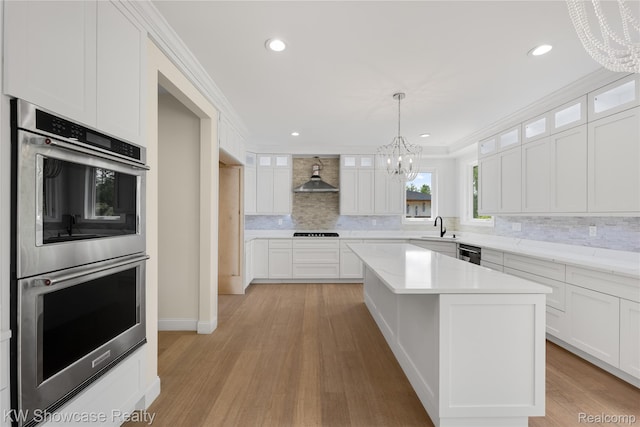 5245 Buell Dr, Commerce Twp, MI 48382 - kitchen featuring double oven, a chandelier, wall chimney exhaust hood, backsplash, and dishwashing machine