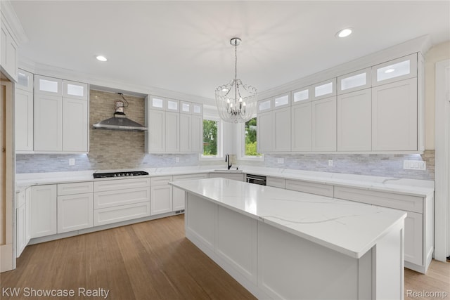 5245 Buell Dr, Commerce Twp, MI 48382 - kitchen featuring a sink, black cooktop, a chandelier, light wood-type flooring, and wall chimney range hood