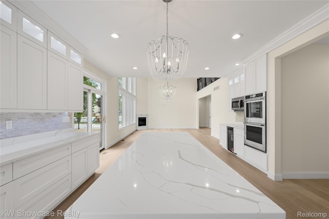 5245 Buell Dr, Commerce Twp, MI 48382 - kitchen with appliances with stainless steel finishes, a chandelier, light wood-style floors, tasteful backsplash, and recessed lighting