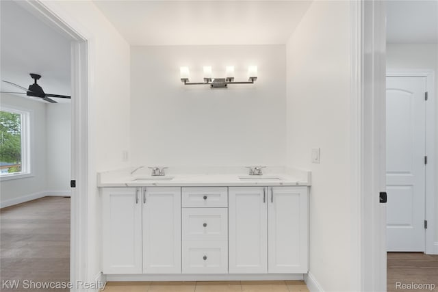 5245 Buell Dr, Commerce Twp, MI 48382 - bathroom featuring baseboards, a ceiling fan, wood finished floors, and double vanity