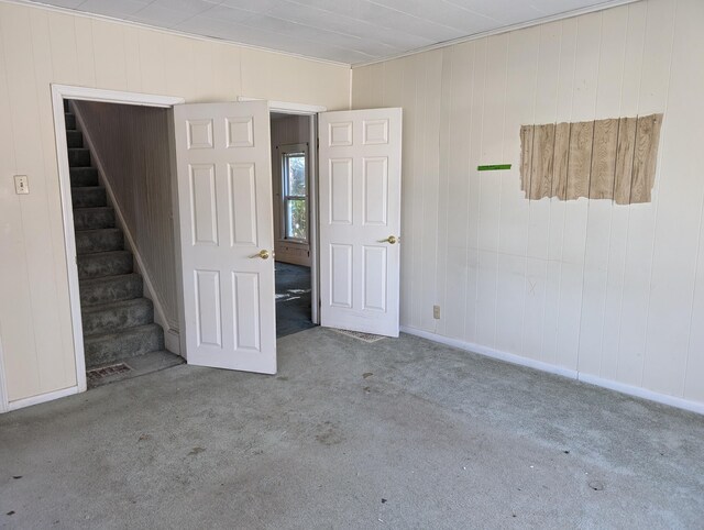 6651 Berrien St E, Eau Claire, MI 49111 - carpeted empty room with stairs, wood walls, and baseboards