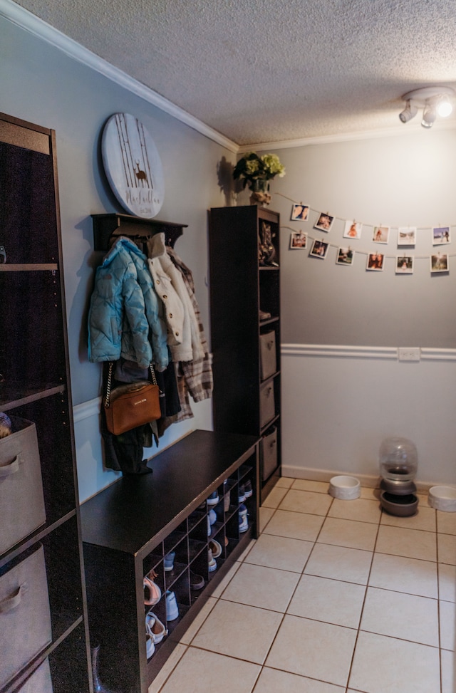 mudroom with tile patterned floors, ornamental molding, and a textured ceiling