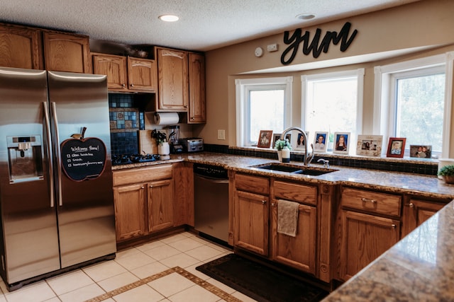 kitchen featuring plenty of natural light, appliances with stainless steel finishes, light tile patterned floors, and sink