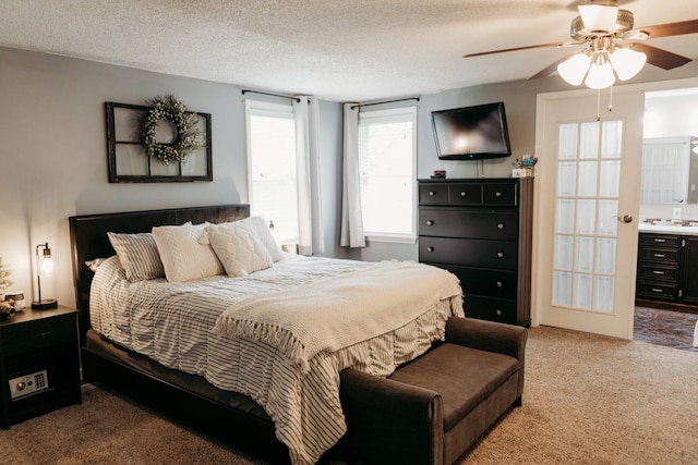 carpeted bedroom featuring ensuite bathroom, a textured ceiling, and ceiling fan