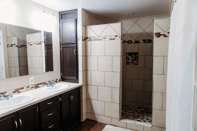 bathroom with a tile shower, vanity, hardwood / wood-style flooring, and tasteful backsplash