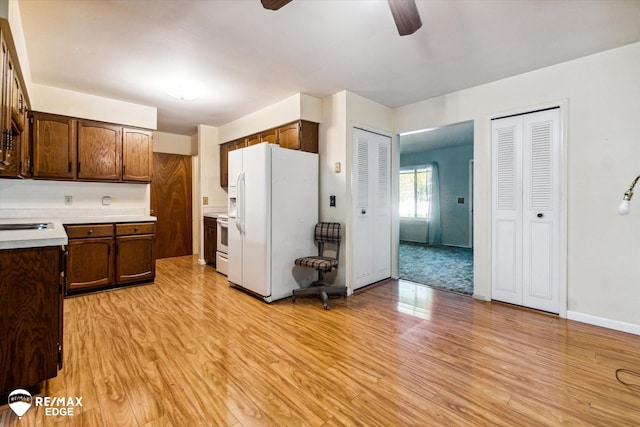 kitchen featuring ceiling fan, white appliances, sink, and light hardwood / wood-style flooring