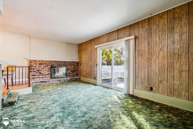 unfurnished living room featuring carpet flooring, wooden walls, and a fireplace