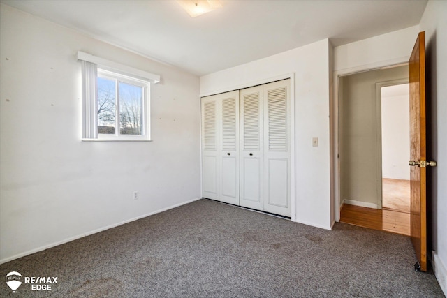 unfurnished bedroom featuring a closet and dark colored carpet