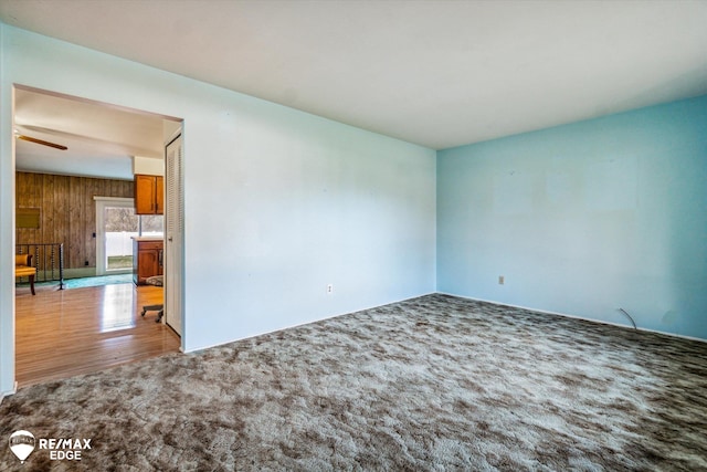 unfurnished room with wood walls, ceiling fan, and light wood-type flooring