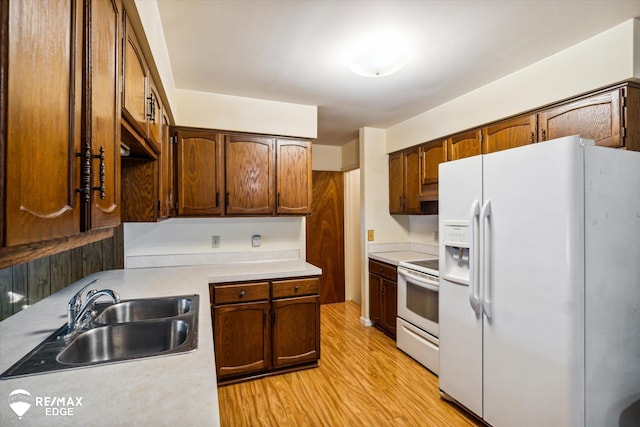 kitchen featuring white appliances, light hardwood / wood-style floors, and sink