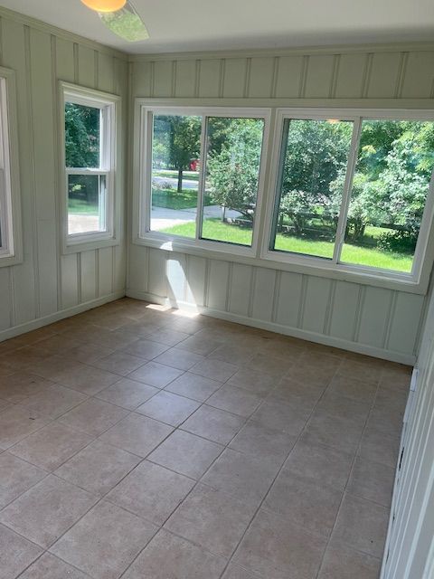 unfurnished sunroom featuring ceiling fan