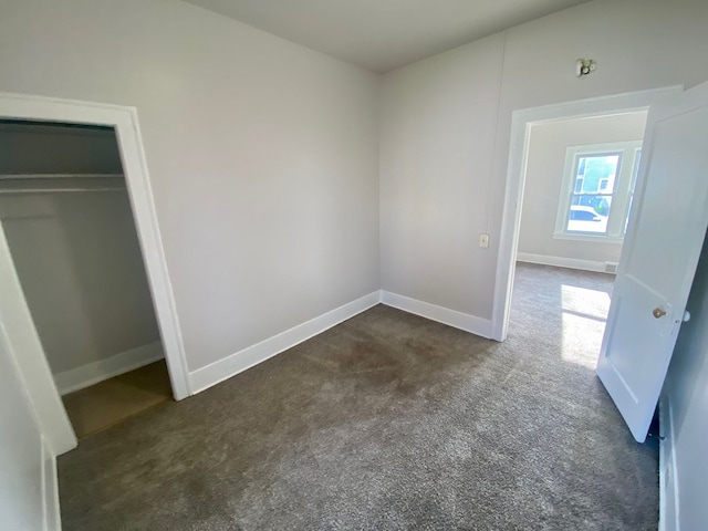 unfurnished bedroom featuring dark colored carpet and a closet