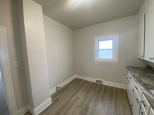 interior space with light wood-style floors, baseboards, and visible vents