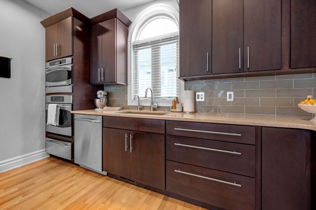 kitchen featuring light hardwood / wood-style floors, decorative backsplash, sink, dark brown cabinetry, and stainless steel appliances